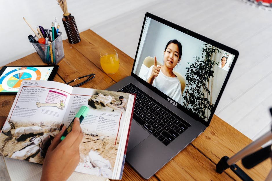 Image of a person teaching online with a computer and world map in the background